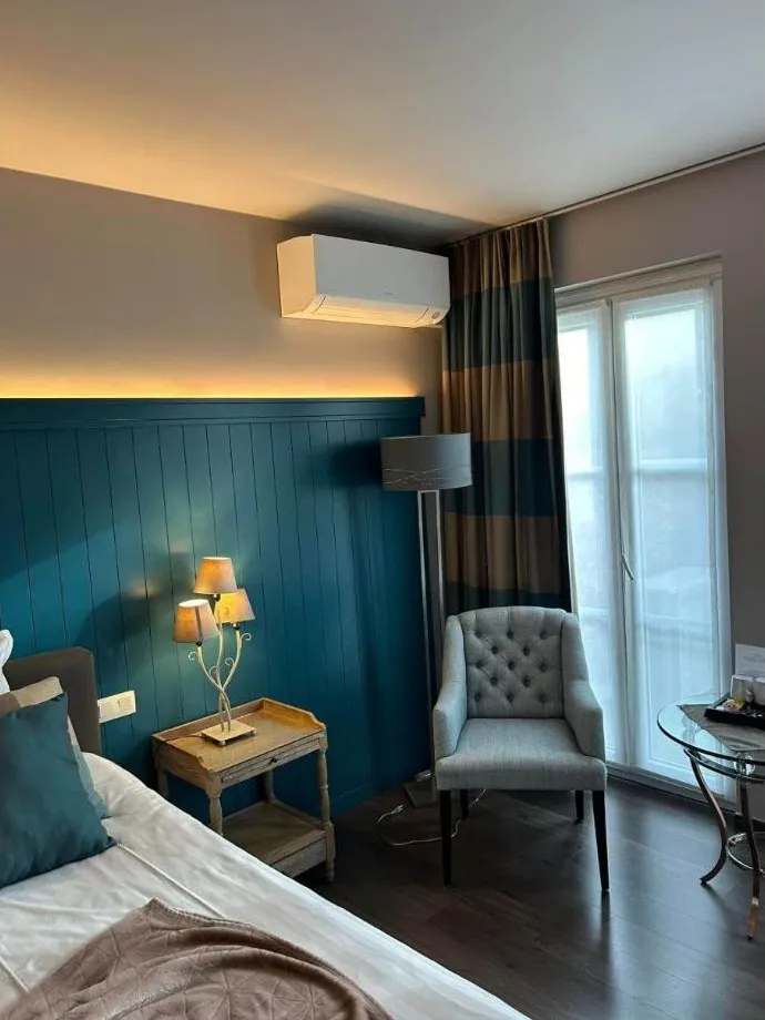 Airco-binnenunit boven het raam in een kamer met blauwe lambrisering