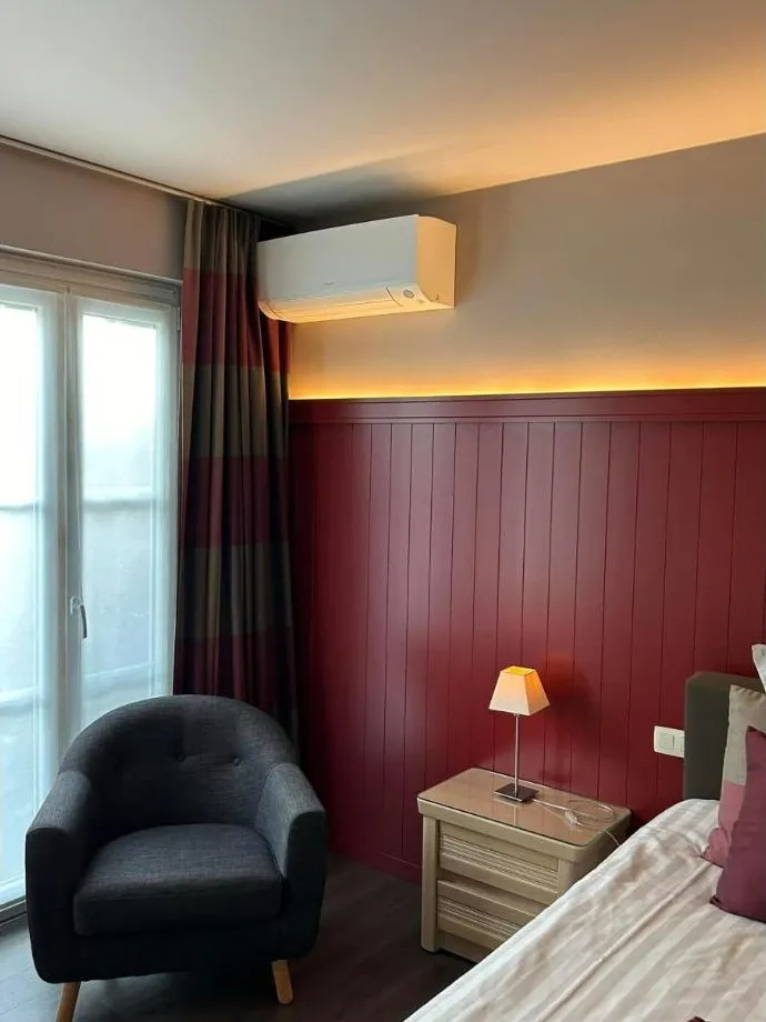 Airco-binnenunit in een kamer met rode lambrisering, zonder zichtbare leidingen