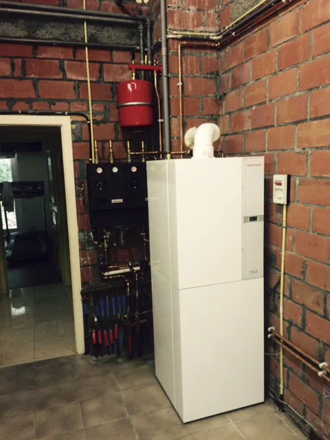 Staande verwarmingsketel in een technische ruimte met bakstenen muren